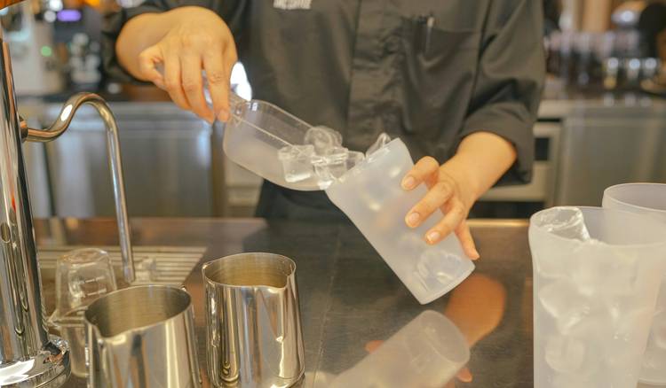 Chef measuring bleach to prepare sanitizer solution in a commercial kitchen