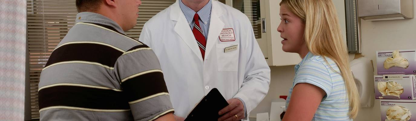 Patient discusses abdominal cramps with a physician—a common symptom of foodborne illness