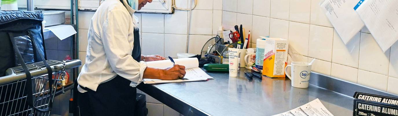 Georgia food safety manager checks temperature logs inside a busy restaurant kitchen